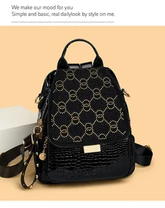 Detail of black crocodile texture leather backpack with gold studded interlocking rings