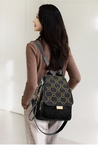 Detail of black crocodile texture backpack with gold rivets and metallic chains