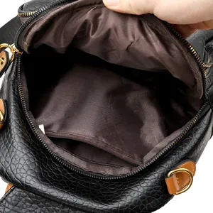 Interior view of black pebbled leather backpack showing brown lining and zippered pocket