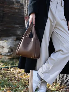 Close-up of caramel brown lychee leather bucket bag with gold protective metal feet