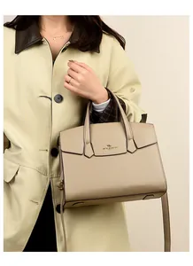 Dettaglio della borsa in pelle beige con trama litchi e logo dorato con manici