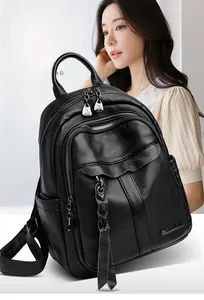 Detail of black litchi texture leather backpack with metal logo and zipper tassels