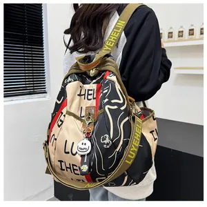 Détail d'un sac à dos graffiti tendance avec larges bretelles olive et pendentif smiley