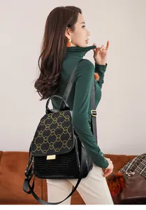 Detail of crocodile-textured leather backpack with golden rivet interlaced ring pattern