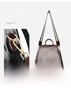 Detailed view of gold-tone metal hook and colorful woven shoulder strap on leather backpack