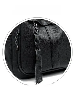 Detail of black lychee grain leather backpack featuring woven tassel and metal zipper
