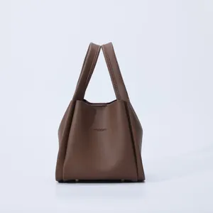 Close-up of dark brown lychee texture leather handbag with silver protective bottom feet