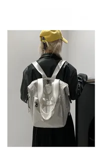 Model wearing a minimalist cream waterproof nylon backpack with multiple zipper pockets