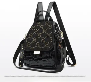 Side view of black faux-crocodile backpack with studded interlocking logo and metallic zippers