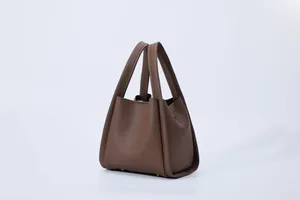 Detail of dark brown lychee leather bucket bag with metal studs and hand-stitched finish