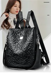 Détail d'un sac à dos en cuir noir avec broderie florale 3D et texture matelassée