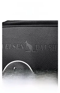 Detail view of premium black litchi pattern leather and polished hardware logo on backpack