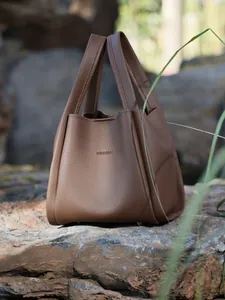 Detailed macro view of brown lychee grain leather bucket bag with HOCOMU brand logo