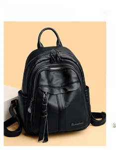 Close-up of black lychee grain leather backpack with silver zippers and woven tassels