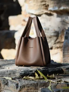 Close-up of brown litchi pattern leather texture and metal studs on bucket bag