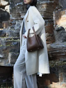 Brown lychee pattern bucket bag styled with a white coat in an outdoor autumn setting