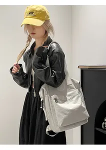 Close-up of cream waterproof nylon backpack featuring a round R logo on the front pocket