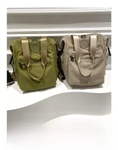 Detail view of khaki and beige nylon backpacks featuring a round R logo and zip pockets