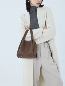 Detailed view of brown lychee leather bucket bag with bottom anti-wear gold metal rivets
