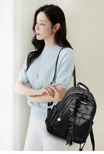 Close-up of litchi texture black leather backpack featuring multiple metal zipper pockets