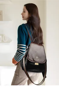 Detail of vintage leather backpack showing kangaroo logo and colorful woven shoulder strap