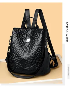 Détail d'un sac à dos noir matelassé avec fleurs en relief 3D et logo métallique
