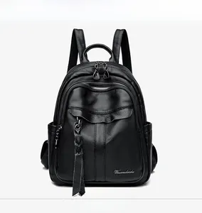 Front detail of black litchi grain leather backpack with woven fringe tassel and side pockets