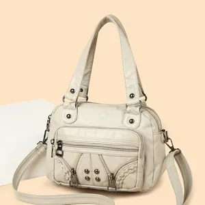 Creamy white washed leather hobo bag with punk rivets and woven edge detailing