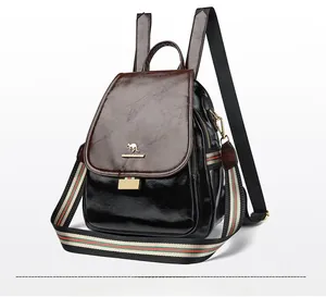 Close-up of leather backpack featuring red and green striped canvas strap and gold hardware