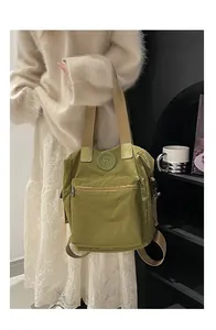 Detail of green nylon tote bag with durable beige shoulder straps and circular logo