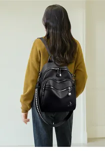 Detail view of black pebble leather backpack with multiple zippers and patterned strap