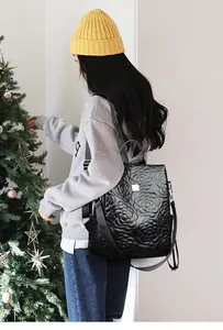 Détail d'un sac à dos en cuir noir avec broderie florale 3D et sangles polyvalentes
