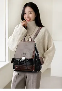 Detail of color-block leather backpack featuring a metal kangaroo logo and silver clasp