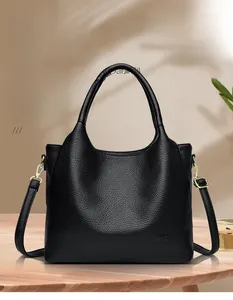 Detail of black pebbled leather handbag with gold hardware and elegant leaf shadows