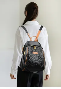 Dettaglio dello zaino trapuntato nero con ricami floreali e finiture in pelle marrone-arancio