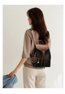 Détail d'un sac à dos en cuir matelassé noir avec cordon marron et breloque sourire