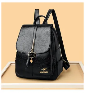 Detalle de mochila de cuero negro con logo de canguro dorado y colgante de gato