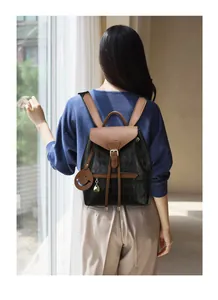 Détail du sac à dos matelassé noir avec rabat en cuir marron et pendentif souriant