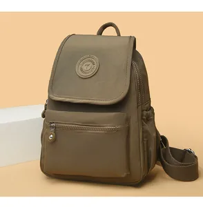 Detalle de la mochila de nailon caqui oliva con bolsillo con cremallera y logo redondo
