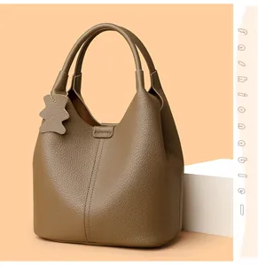 Detail of tan leather bucket bag with litchi texture and a cute bear charm pendant