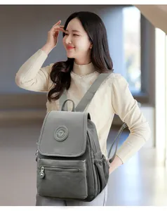 Primer plano de mochila de cuero sintético gris con logo redondo y solapa