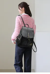 Detalle de mochila de cuero negro con logo de canguro dorado y colgante de gato mono