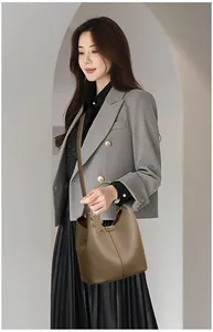 Brown lychee-textured leather bucket bag with top handles and leaf pendant detail