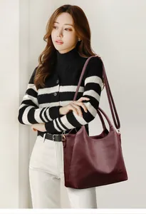 Detail of burgundy lychee grain leather tote bag with gold hardware and strap