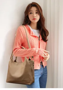 Brown lychee grain hobo bag with logo detail shown on a model with orange cardigan