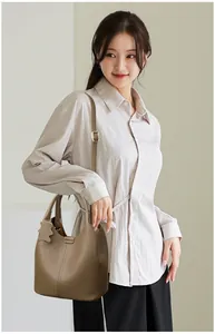 Close-up of khaki leather bucket bag with litchi grain and cute bear charm pendant