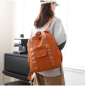Rückansicht eines Modells mit dem orangefarbenen Nylon-Rucksack für Reise und Alltag