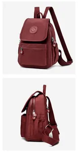 Detalle de mochila de nailon color burdeos con bolsillo frontal y correa ajustable
