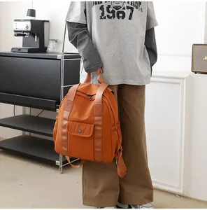 Detailansicht des karamellfarbenen Nylonrucksacks mit breitem Griff und Fronttasche
