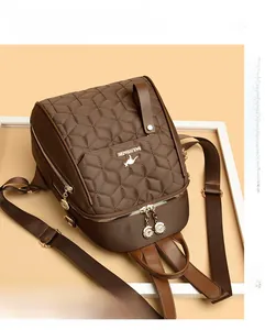 Close-up of diamond-quilted stitching and gold zipper detail on dark brown backpack